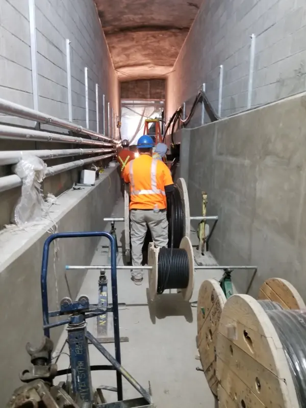 Electricians installing cabling in a commercial building service tunnel